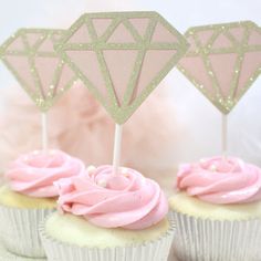 three cupcakes with pink frosting and diamond decorations on top, sitting next to each other