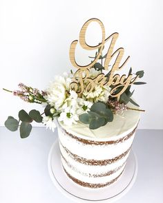 there is a cake with flowers on it and the word oh baby spelled in gold