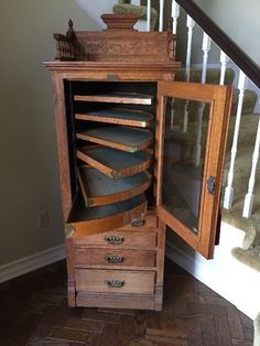 an old wooden cabinet with many drawers on it's sides and stairs in the background