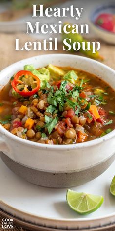 hearty mexican lentil soup in a white bowl with limes on the side