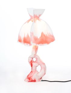 a red and white lamp with a pink shade on it's base, sitting on a white surface