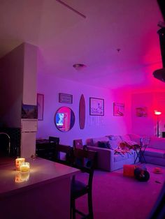 a living room filled with furniture and pink lighting