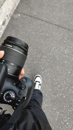 a person holding a camera up to their face with one hand and the other leg behind them