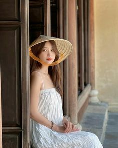 a woman wearing a hat sitting on the side of a building