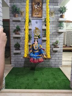 an idol is displayed in front of a brick wall with yellow flowers and greenery