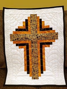 a quilted wall hanging on the back of a couch with a cross in it