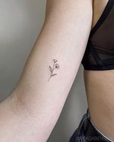 a woman's arm with a small flower tattoo on the left side of her arm