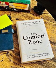 the comfort zone book is next to a wallet and other books on a wooden table