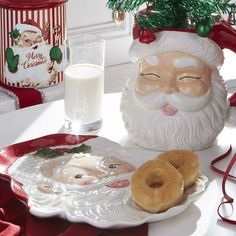 a plate with doughnuts on it next to a glass of milk and santa clause mug