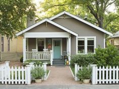 a small house with a picket fence around the front yard and porches on both sides