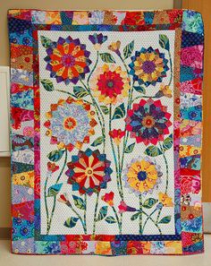 a quilted wall hanging with colorful flowers on it