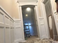 a ladder is in the corner of a room with white walls and trim around it