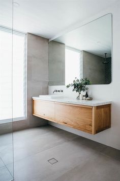 a bathroom with two sinks and a large mirror on the wall above it, in front of a window