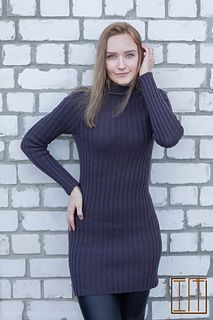 a woman standing in front of a brick wall wearing black leggings and a turtle neck sweater