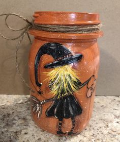 an orange jar with a witch painted on it