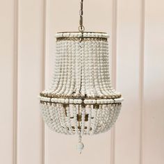 a chandelier with beads hanging from it's sides in front of a white wall