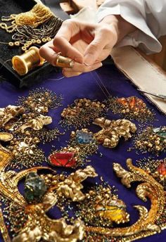 a close up of a person working on an elaborate piece of cloth with beads and chains