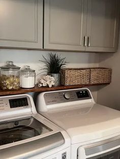 a washer and dryer in a laundry room with cabinets above them, next to a window