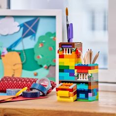 a desk with legos, pens and pencils on it in front of a painting