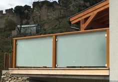 a wooden and glass balcony on the side of a building with a mountain in the background