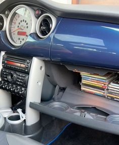 the interior of a sports car with magazines and cd's on the dash board