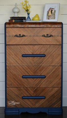 a wooden dresser with blue handles and drawers on it's sides, against a white wall