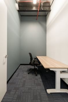 an empty office space with a desk and chair in the corner, next to a door