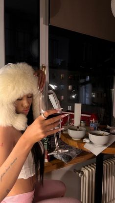 a woman wearing a santa hat and holding a wine glass looking at her cell phone