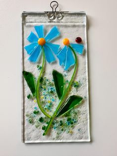 two blue flowers with green leaves and gummy dots in the middle on a white background