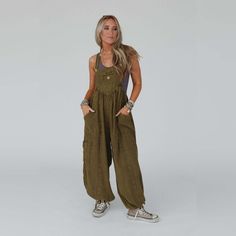 Get ready to look effortlessly boho - chic and ready - to - go in the Coastal Muse Wide Leg Jumpsuit! Feel authentically you in this cute jumpsuit because it features: Comfortable, lightweight, mineral - washed Cotton gauze fabric Loose and slouchy jumpsuit overall silhouette Classic square neckline with adjustable button straps Flattering gathered pointed center seams Oversized wide pant legs with unique tied gathered details along the ankles Convenient side pockets, a single cargo pocket along the side, and a center pocket along the bib Pair with: Eye Of The Sun Padded Bralette, Cherish The Moment Lace Top and Neon Lights Stacked Bracelet. *Due to lighting and differences in monitors, actual colors may vary slightly from what appears online. Model is 5'8" and wearing a size Small. Approx Hippie Summer Overalls With Pockets, Casual Khaki Jumpsuits And Rompers For Summer, Casual Relaxed Fit Overalls For Vacation, Bohemian Jumpsuits And Rompers With Pockets For Spring, Relaxed Fit Overalls For Spring Vacation, Bohemian Overalls With Pockets For Spring, Summer Khaki Relaxed Fit Jumpsuits And Rompers, Casual Linen Jumpsuits And Rompers, Bohemian Cotton Overalls For Spring