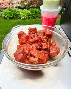 a glass bowl filled with meat sitting on top of a table next to a cup