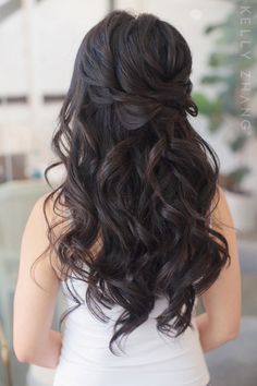 the back of a woman's head with long dark hair and curls in it