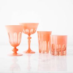 an assortment of pink glassware on a white surface