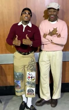 two black men standing next to each other in front of a wooden paneled wall