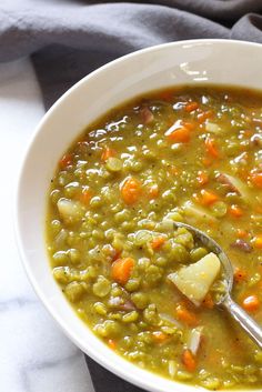 a white bowl filled with peas and carrots next to a gray napkin on top of a table