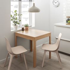 a table with two chairs and a clock on the wall above it in a white room