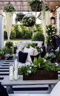 an outdoor living area with potted plants and candles on the table in front of it