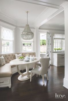 a dinning room table with white chairs around it and a bench in the middle