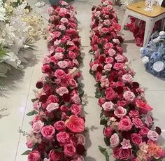 two rows of pink and red flowers in a flower shop