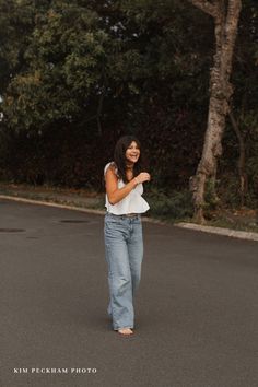 a woman standing in the middle of a parking lot with her hand on her hip