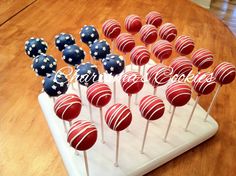 red, white and blue cake pops are arranged on a tray with wooden table top