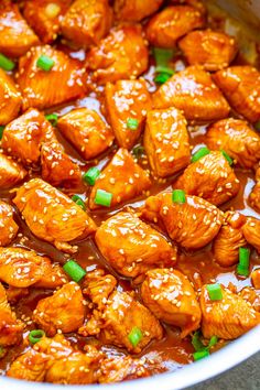 a bowl filled with chicken covered in sauce and green onions