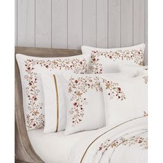 a bed with white sheets and pillows on top of it in front of a wooden headboard