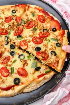 a pizza with olives, tomatoes and other toppings being cut by a knife