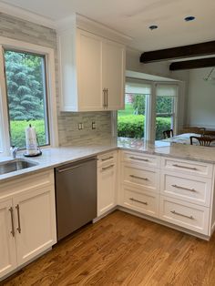 a kitchen with white cabinets and wood floors