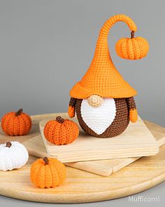 an orange knitted gnome's hat and pumpkins on a wooden tray with grey background