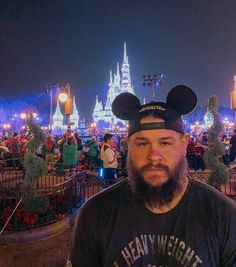 a man with a mickey mouse ears hat at disneyland in front of a crowd of people