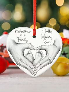 a christmas ornament with two hands holding a baby's feet in the shape of a heart