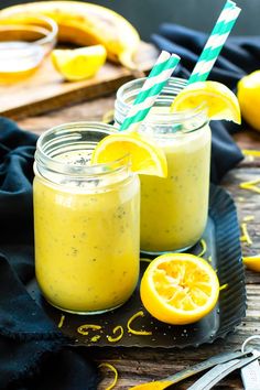 two mason jars filled with lemon custard and topped with striped straws on a black plate