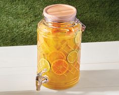 a mason jar filled with lemonade and limes on a table next to grass